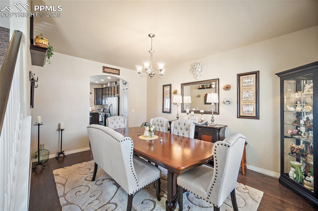 Image 22 of 50: Dining space featuring a chandelier, arched walkways, dark wood-style floor