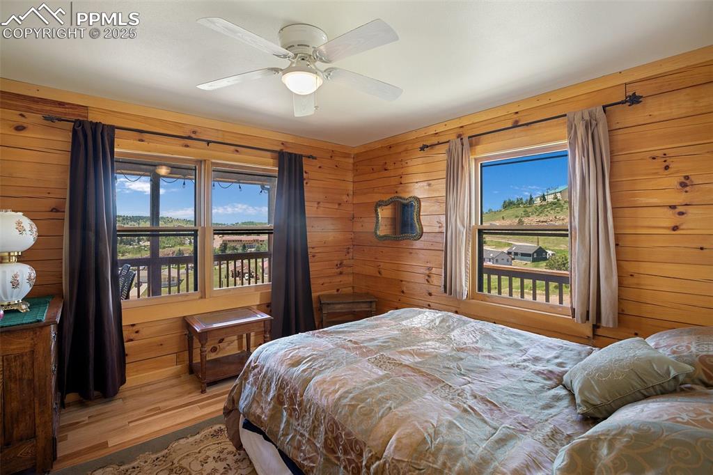 Image 11 of 28: Main level, Bedroom 1 featuring wood walls, wood finished floors, and ceili