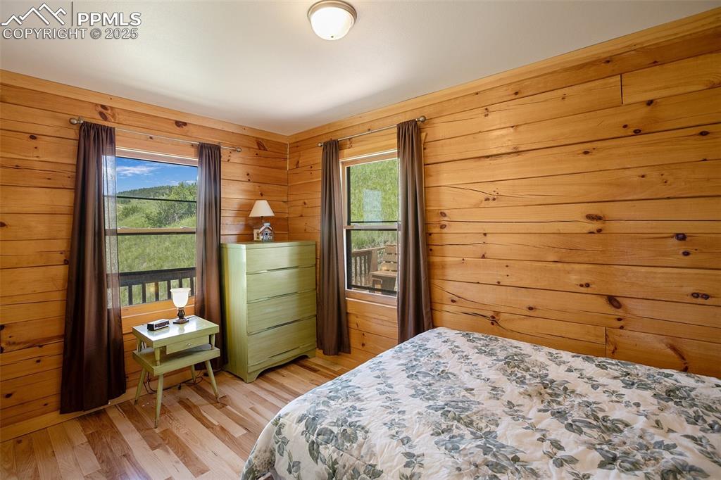 Image 12 of 28: Main level, Bedroom 2 featuring light wood-style flooring and wooden walls