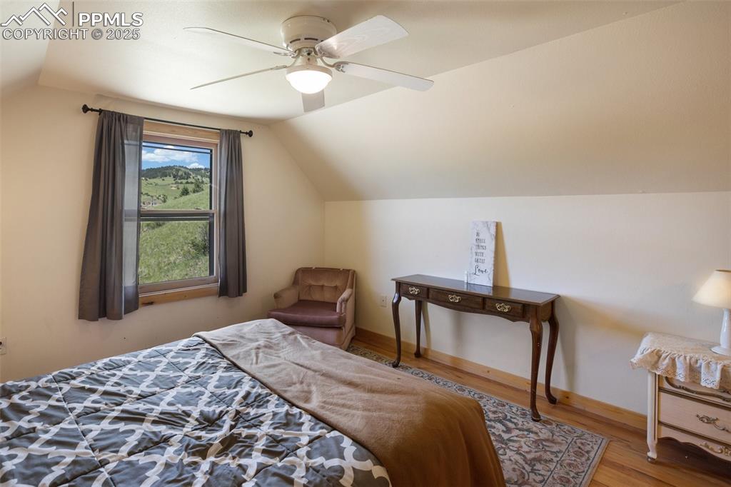 Image 17 of 28: Upper level Bedroom featuring vaulted ceiling, wood finished floors, and a 