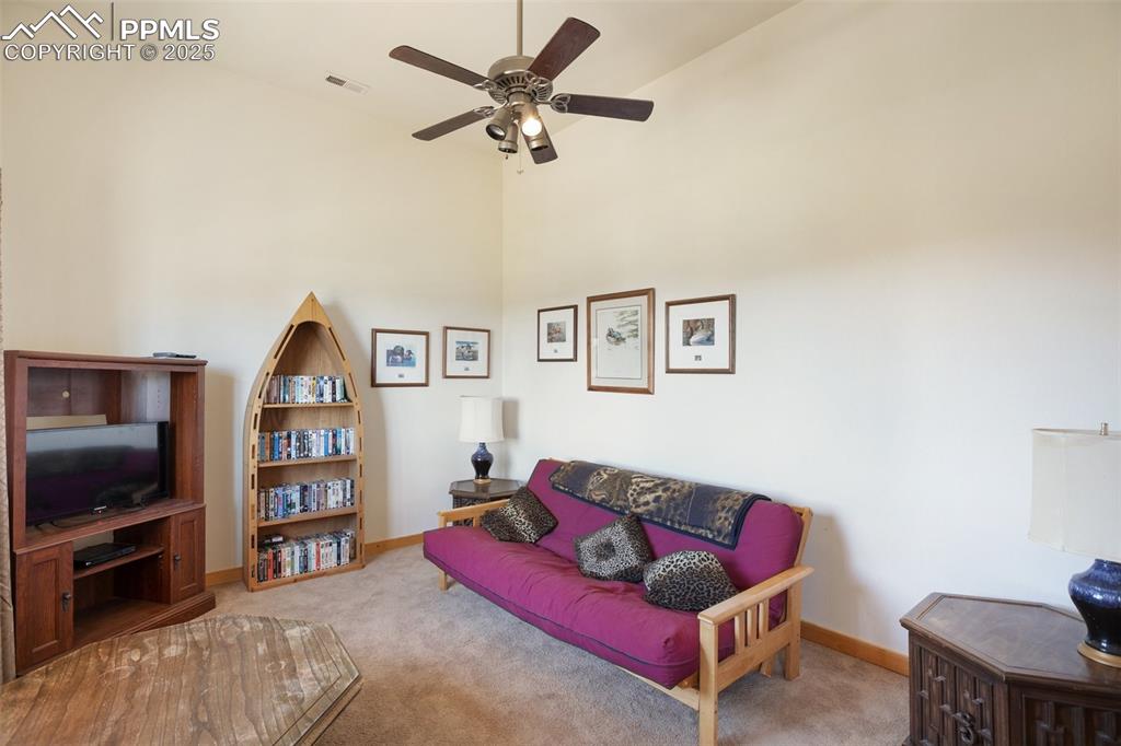 Image 4 of 28: Family room featuring carpet, a ceiling fan, and a high ceiling