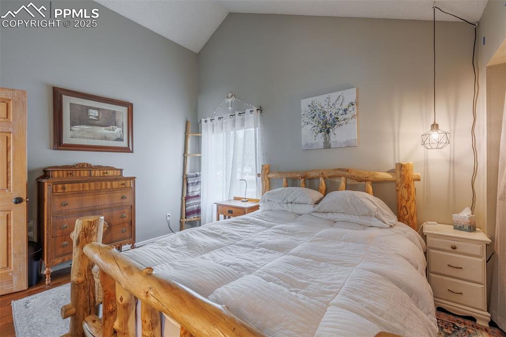 Image 11 of 16: Bedroom with lofted ceiling and wood finished floors