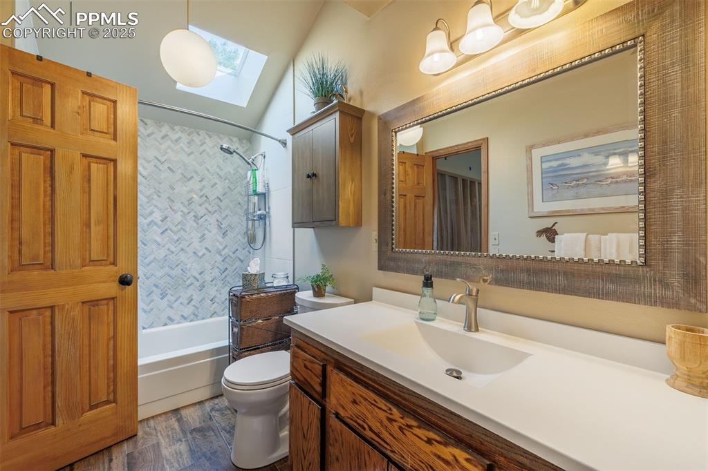 Image 12 of 16: Full bath featuring a skylight, vanity, shower / tub combo and wood finishe