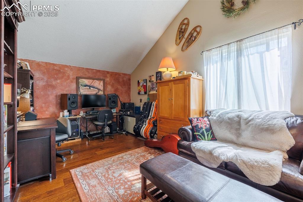 Image 13 of 16: Office space or living room with wood finished floors and vaulted ceiling
