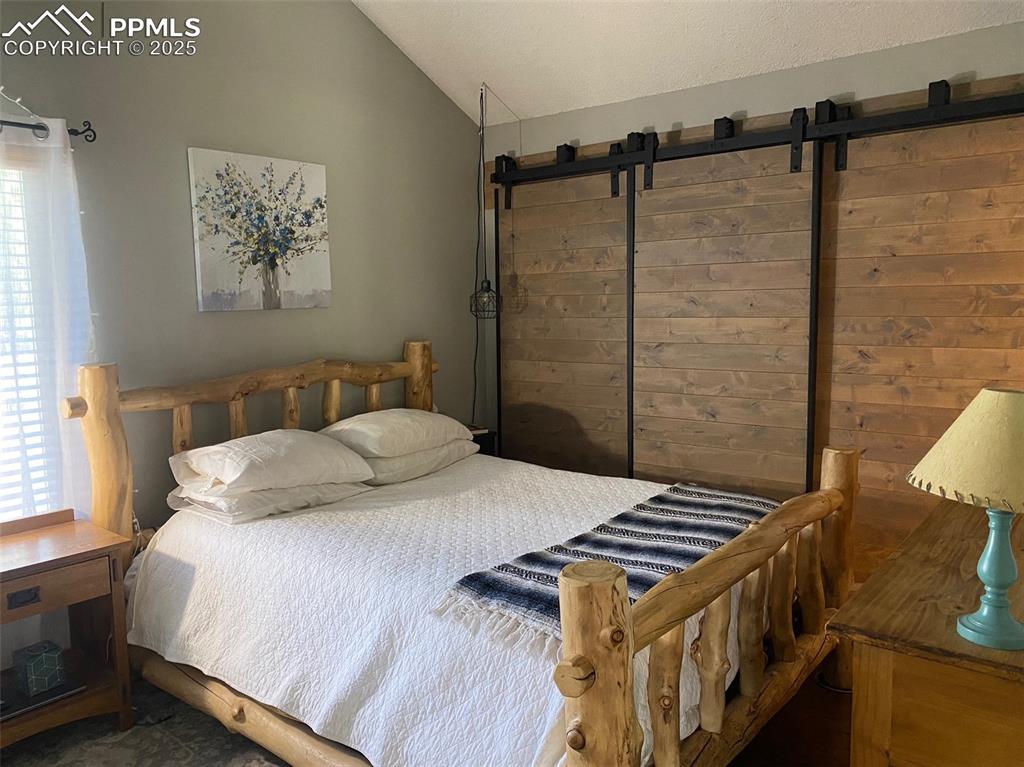 Image 8 of 16: Bedroom with lofted ceiling and a barn door