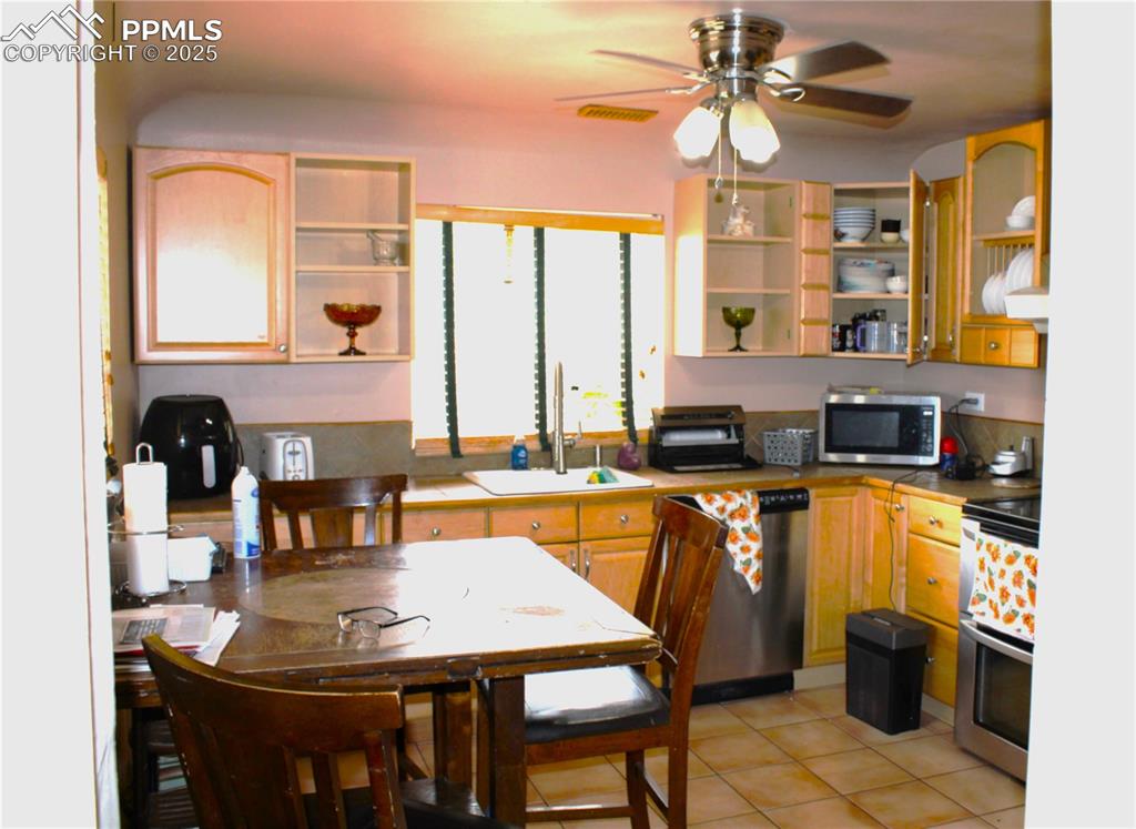 Image 13 of 41: Kitchen with open shelves, appliances with stainless steel finishes, light 