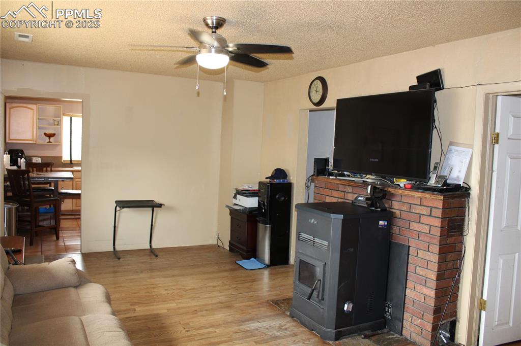 Image 16 of 41: Living area with hardwood floors and pellet stove.