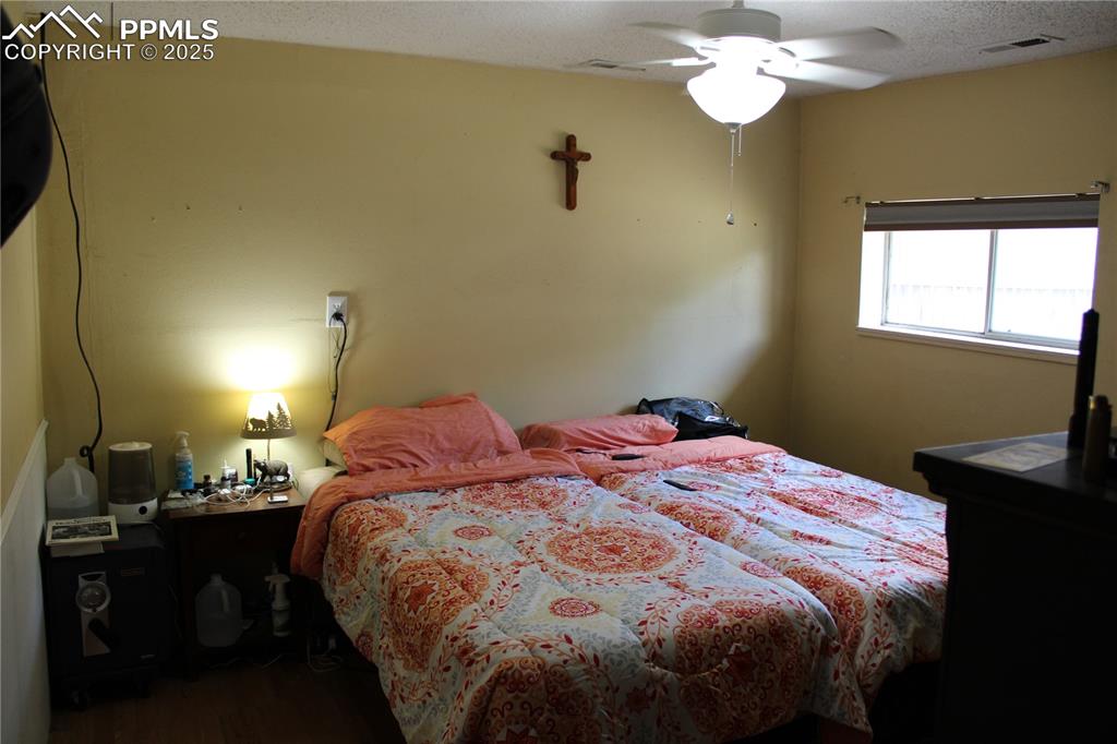 Image 18 of 41: Bedroom featuring wood finished floors, a textured ceiling, and ceiling fan