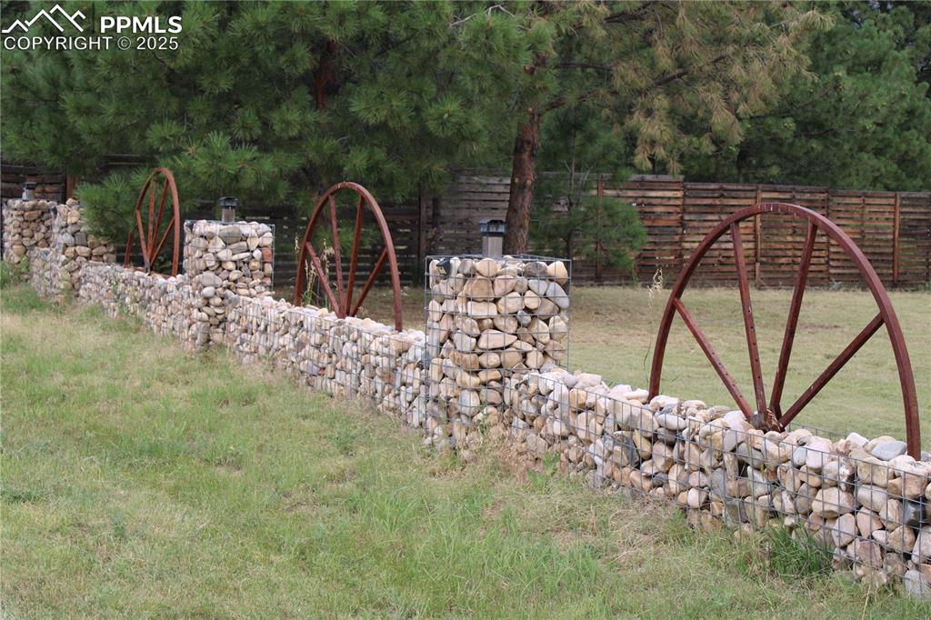 Image 4 of 41: View of side yard with unique stone fencing