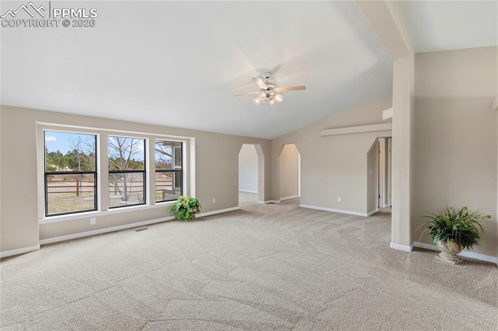Image 18 of 46: Unfurnished room with arched walkways, ceiling fan, and light colored carpe