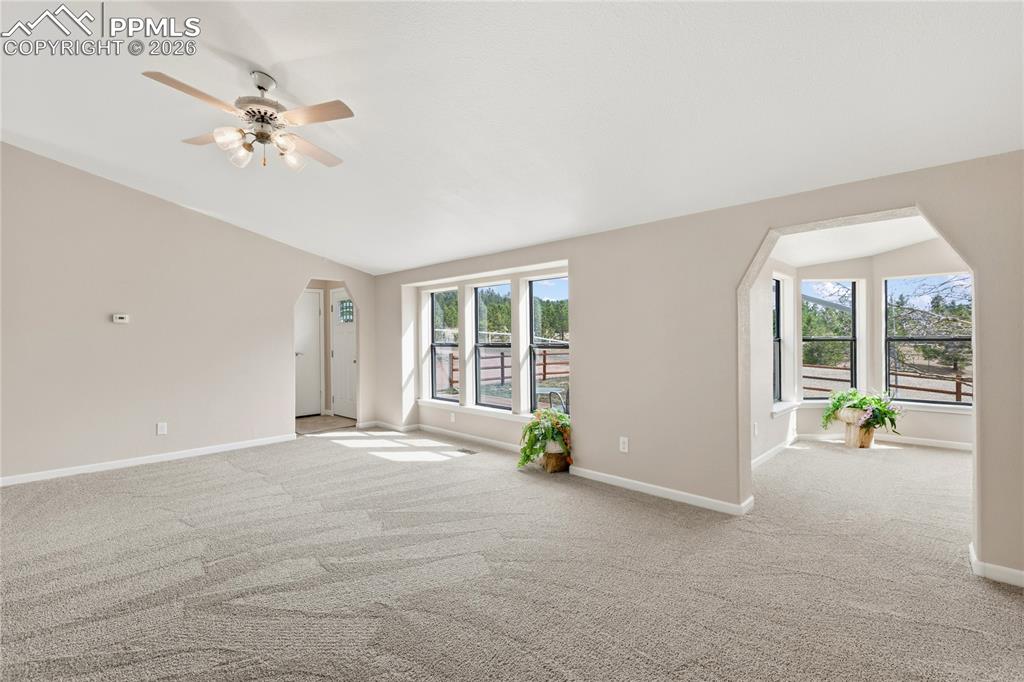Image 19 of 46: Spare room with arched walkways, vaulted ceiling, light colored carpet, and