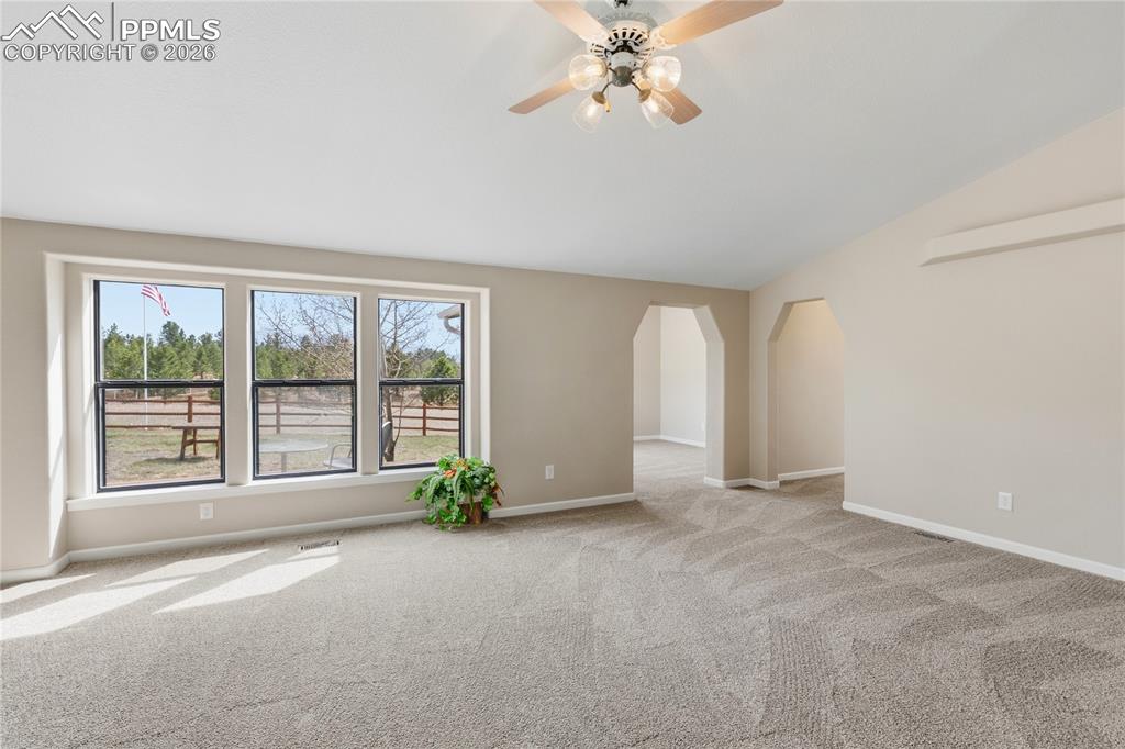 Image 20 of 46: Empty room with ceiling fan, arched walkways, light carpet, and vaulted cei