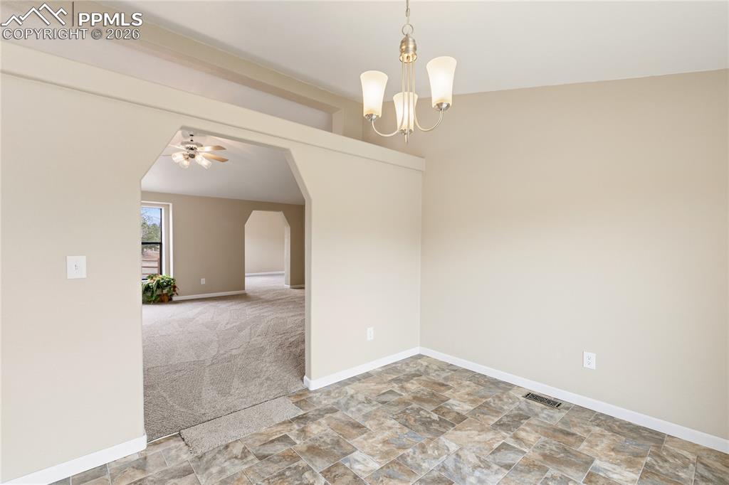 Image 21 of 46: Unfurnished dining area with stone finish flooring, arched walkways, light 