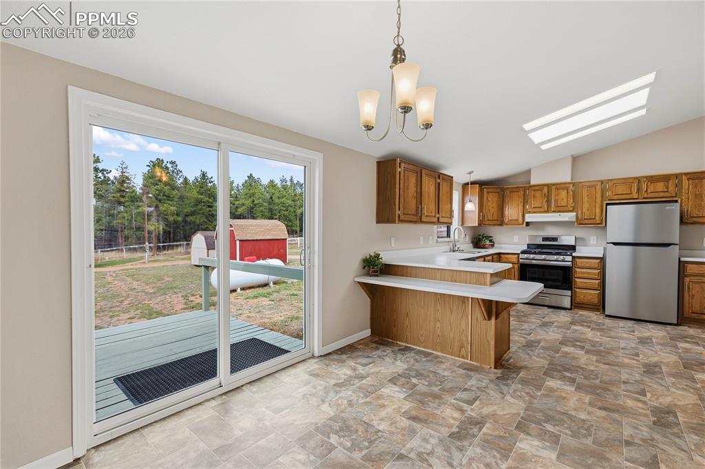 Image 23 of 46: Kitchen with light countertops, stone finish flooring, wood finish cabinets