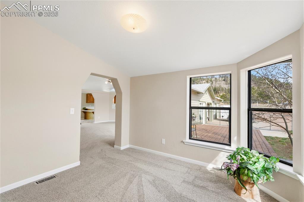 Image 30 of 46: Empty room featuring light colored carpet, arched walkways, and vaulted cei