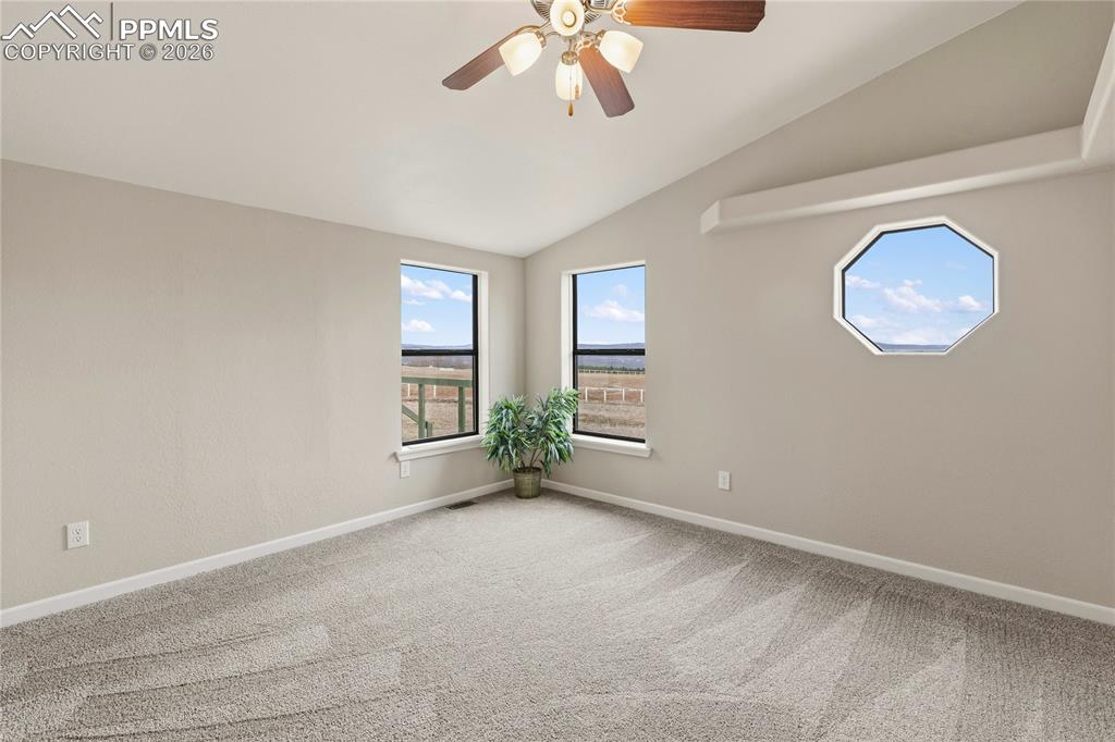 Image 39 of 46: Unfurnished room with ceiling fan, lofted ceiling, and light colored carpet