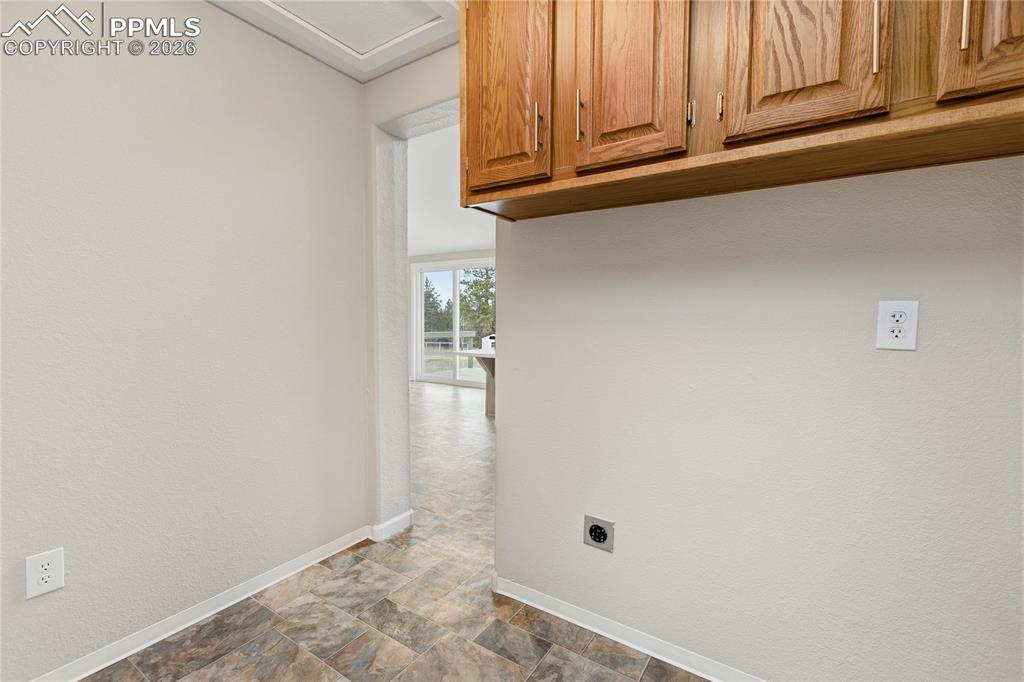 Image 46 of 46: Laundry area featuring stone finish floors, electric dryer hookup, a textur