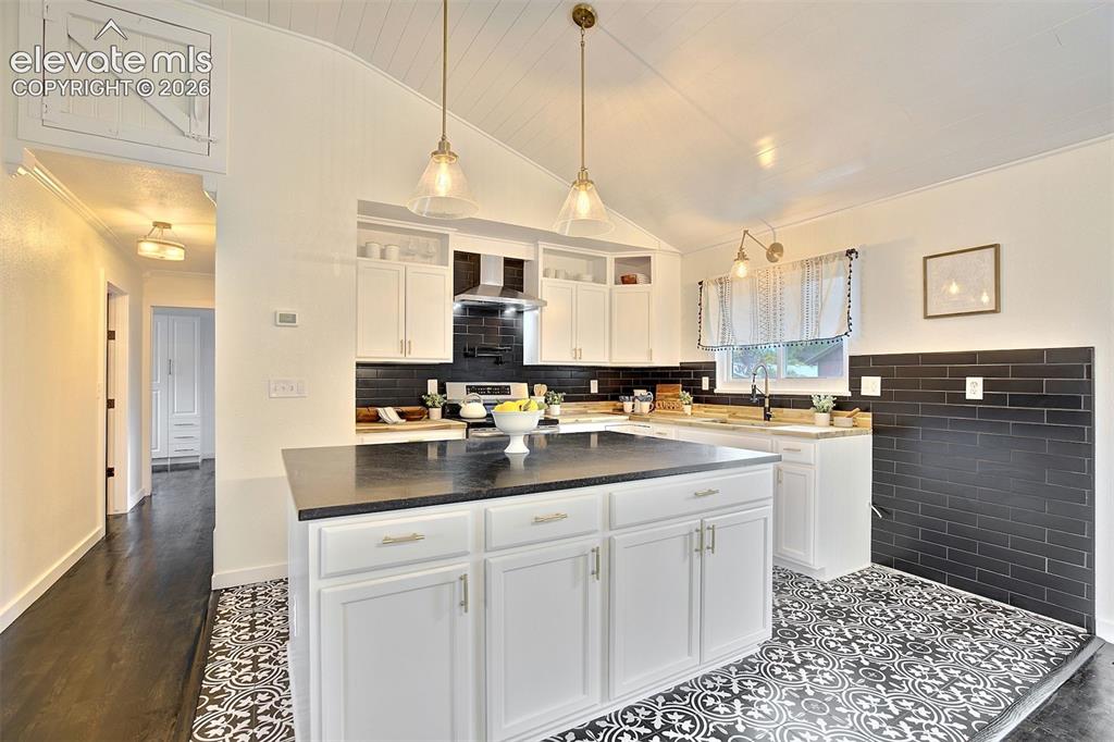 Image 10 of 43: Kitchen featuring white cabinetry, center island with dark countertop, blac