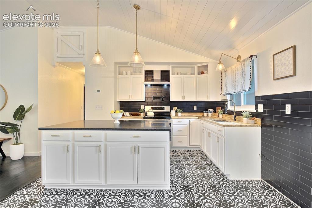 Image 11 of 43: Kitchen featuring a center island with dark countertops, white cabinetry, b