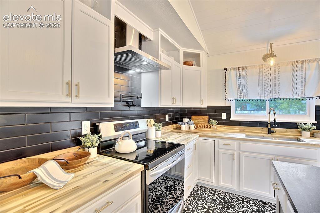 Image 12 of 43: Kitchen featuring white shaker-style cabinetry, black subway tile backsplas