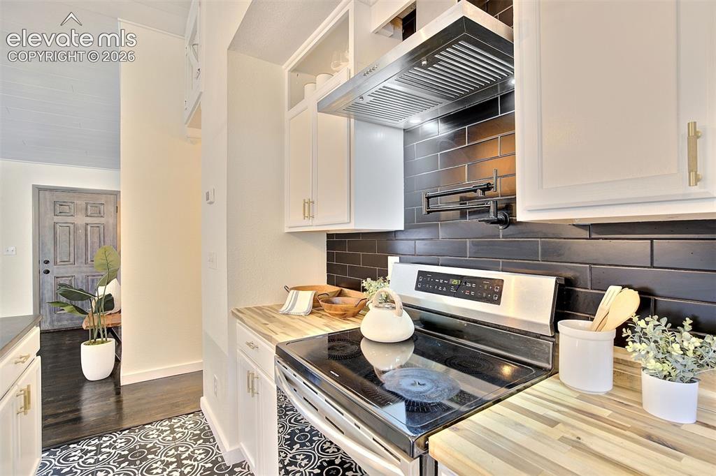 Image 13 of 43: Kitchen featuring white shaker cabinetry, butcher block countertops, black 