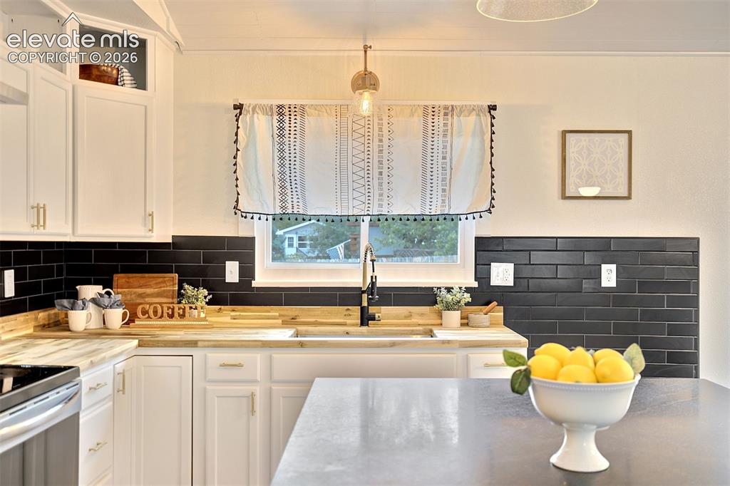 Image 14 of 43: Kitchen featuring white cabinetry with glass-front uppers, wood-finish coun