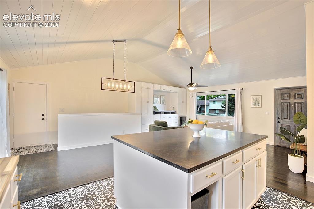 Image 16 of 43: Kitchen featuring a central island with a dark countertop, white cabinetry,