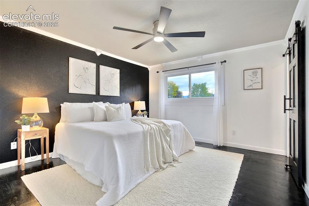 Image 17 of 43: Interior space featuring dark-finished wood flooring, a textured black acce