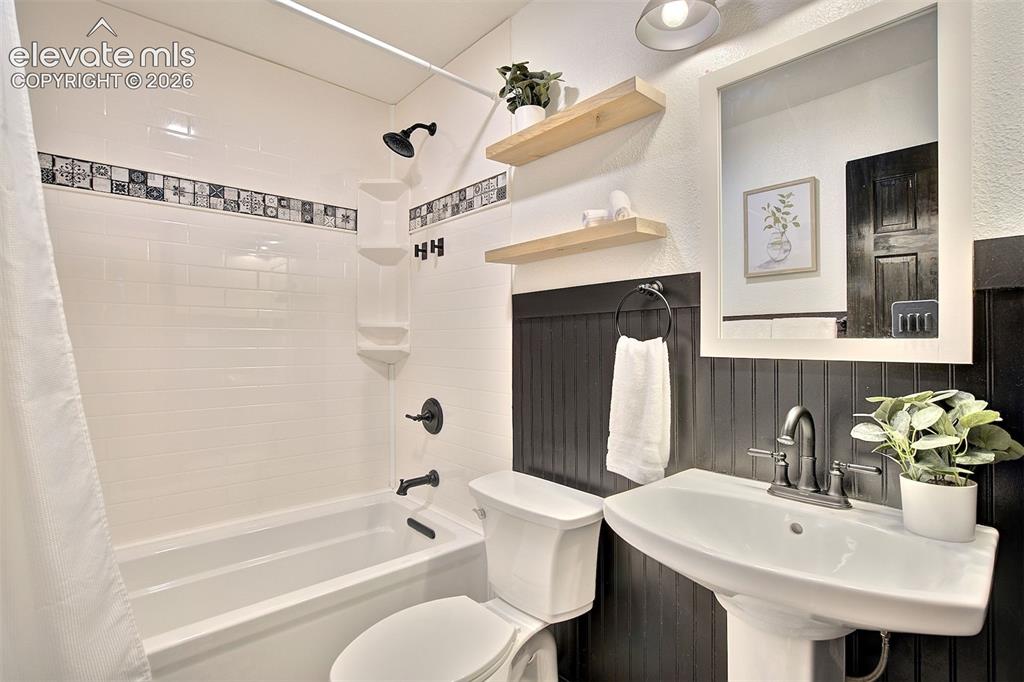 Image 28 of 43: Bathroom featuring a white pedestal sink with dark metallic hardware, a whi
