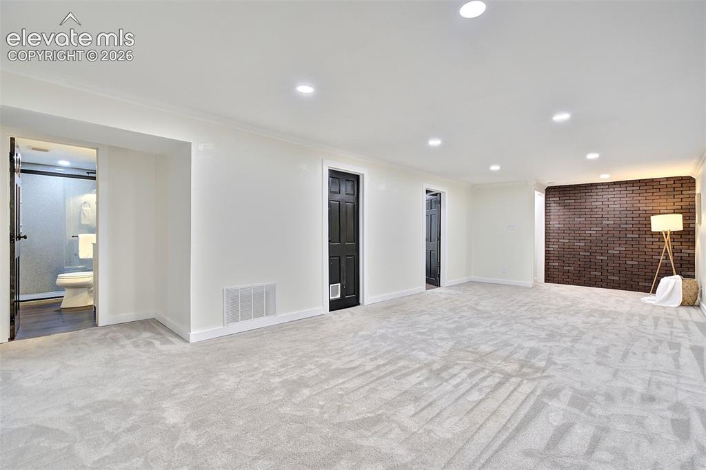 Image 31 of 43: Interior space featuring recessed lighting, a dark brick accent wall, neutr