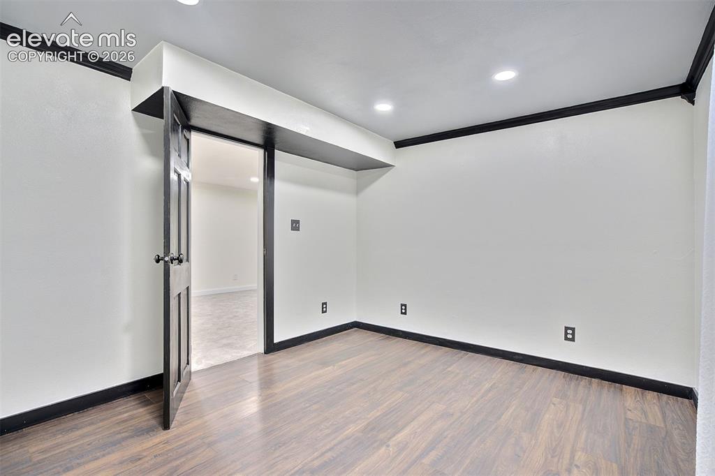 Image 32 of 43: Interior space featuring wood-finish flooring, recessed lighting, and bold