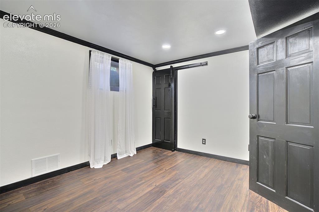 Image 33 of 43: Interior space featuring wood-finish flooring, dark-painted trim and doors,