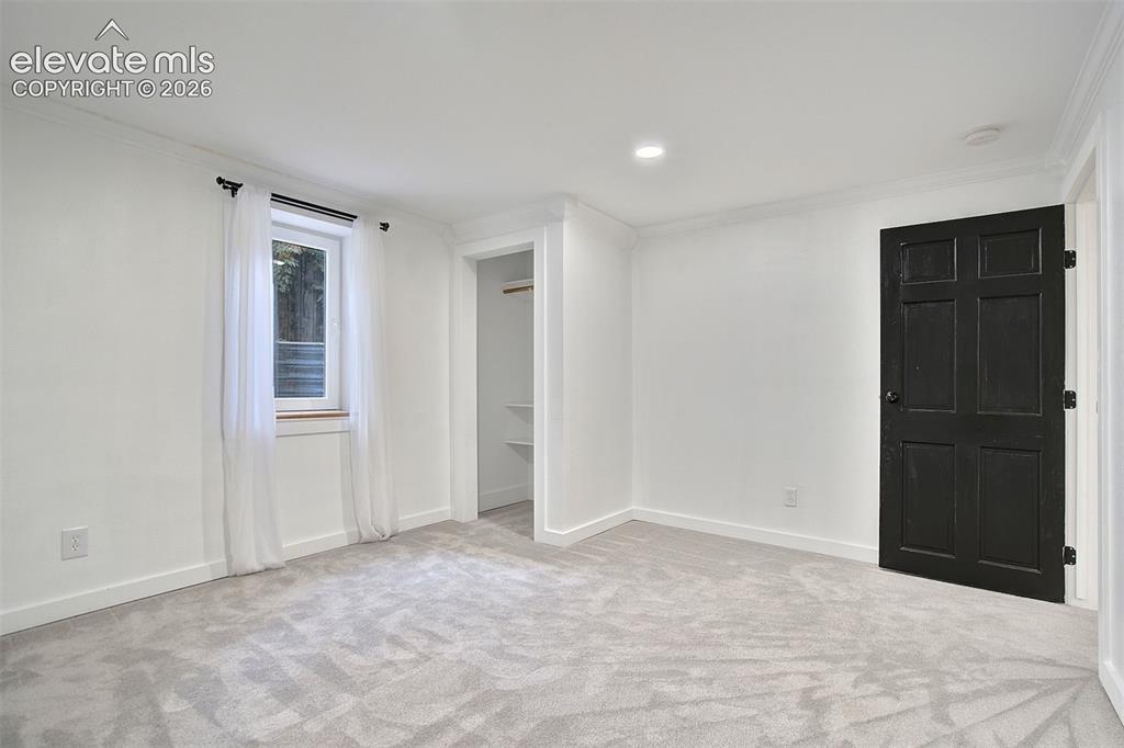 Image 34 of 43: Neutral carpeting, recessed lighting, crown molding, and a six-panel door w