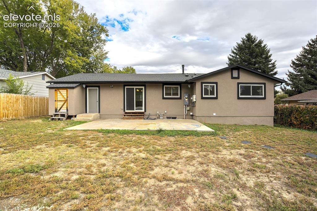 Image 40 of 43: Exterior rear elevation featuring a concrete patio, sliding glass door, and