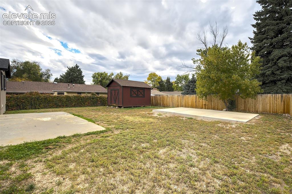 Image 41 of 43: Expansive backyard featuring two concrete pads, a detached wood-frame stora