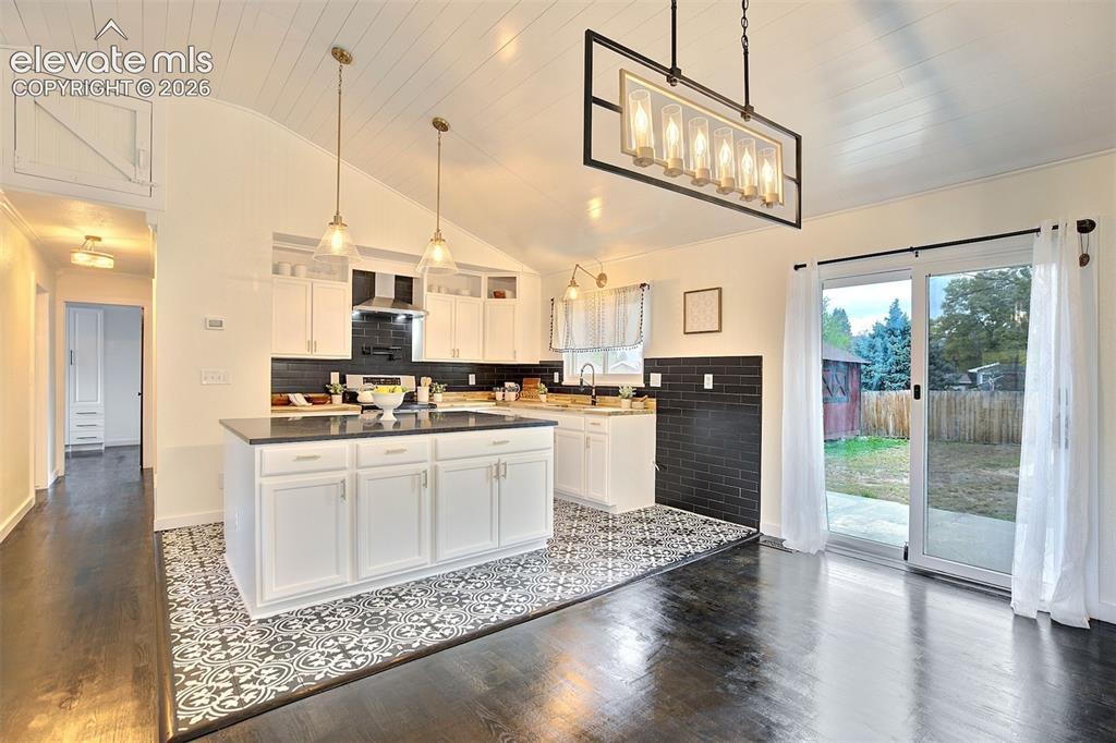 Image 9 of 43: Kitchen featuring a central island with a dark countertop, white cabinetry,