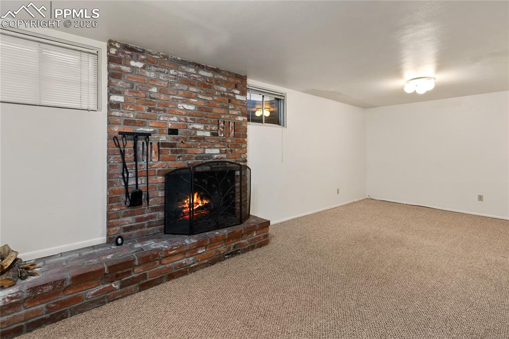 Image 23 of 37: Basement family room features a wood burning fireplace. 