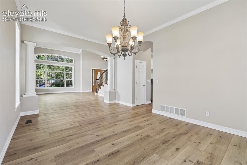 Image 10 of 49: Spacious room featuring wood-finish flooring, a decorative chandelier, and