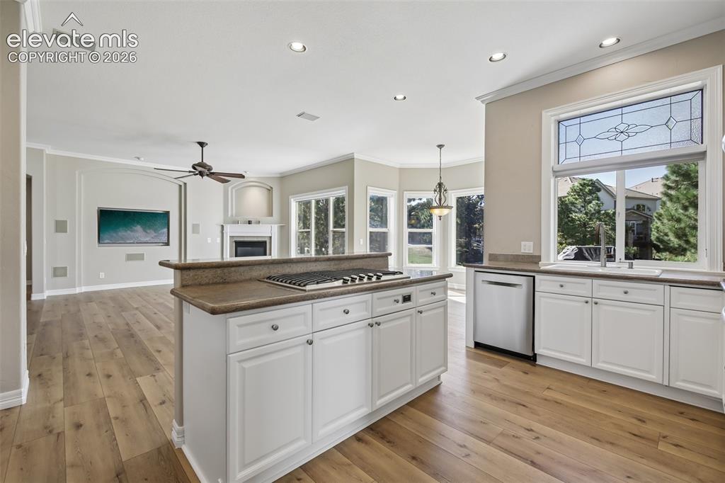 Image 11 of 49: Kitchen island with built-in gas cooktop, white cabinetry, and wood-finish 