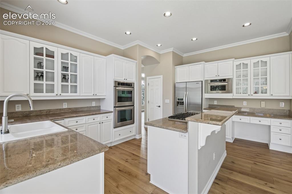 Image 13 of 49: White cabinetry, wood-finish flooring, recessed lighting, stainless steel a