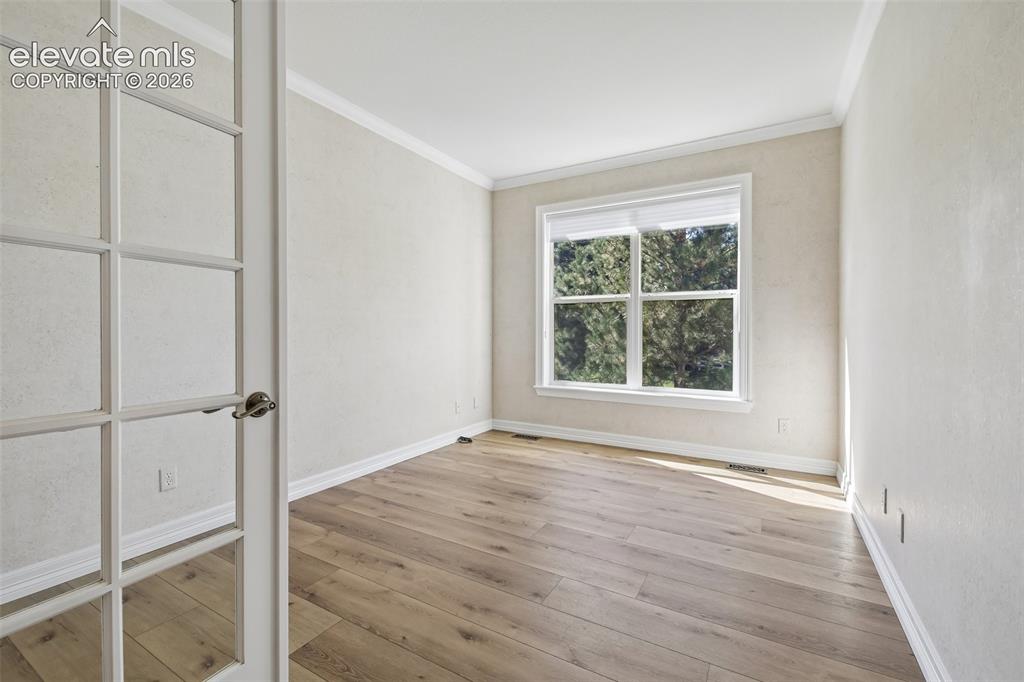Image 16 of 49: Wood-finish flooring, white window trim, white crown molding, white baseboa