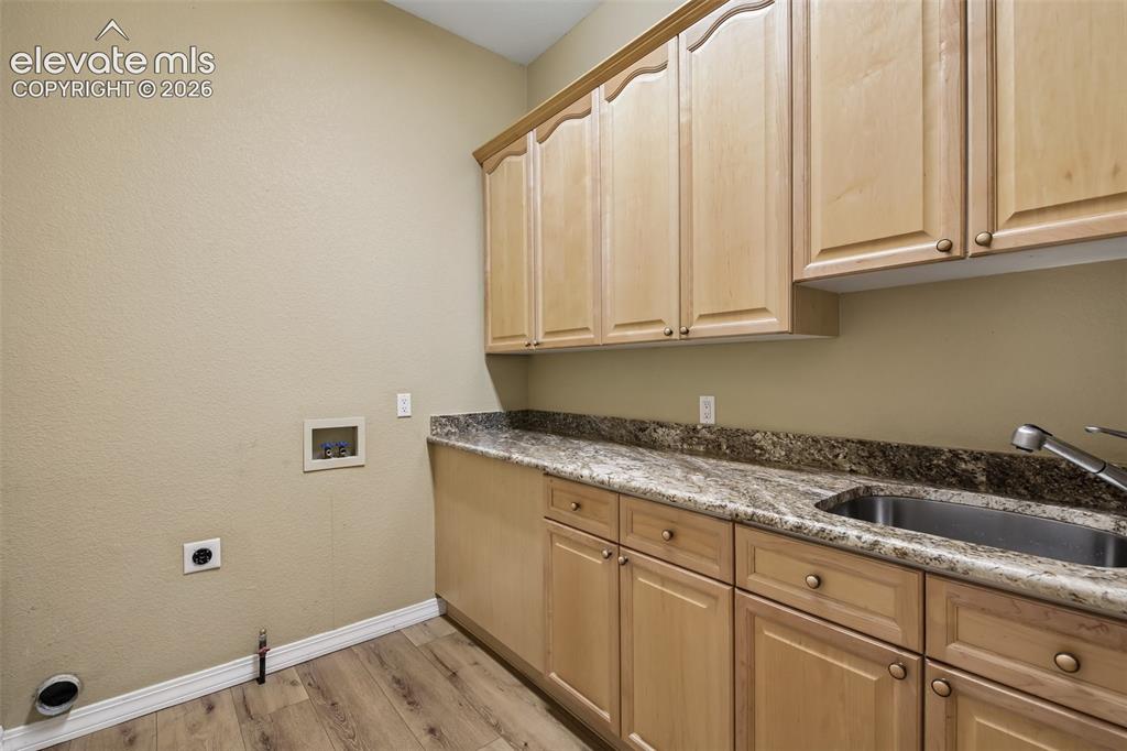 Image 18 of 49: Wood-finish flooring, light-toned cabinetry, stone-finish countertops, stai