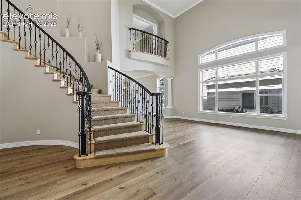 Image 3 of 49: Curved staircase with wrought iron balusters, wood-finish flooring, soaring