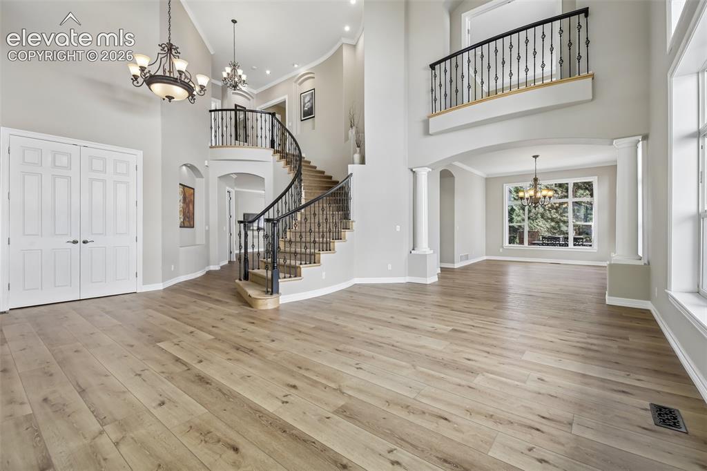 Image 4 of 49: Two-story entryway with a curved staircase featuring wrought iron balusters