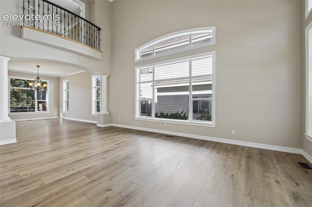 Image 5 of 49: Two-story living area featuring wood-finish flooring, a grand arched entryw