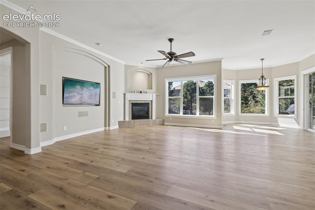 Image 7 of 49: Spacious room featuring wood-finish flooring, a corner fireplace with a whi
