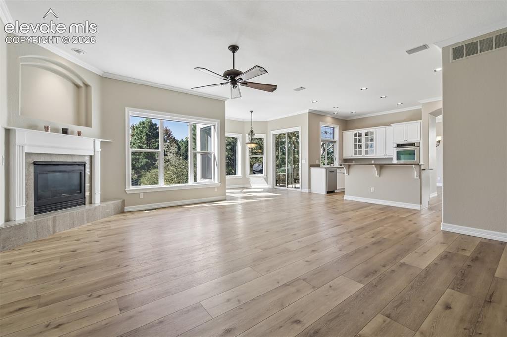 Image 8 of 49: Expansive living area with wood-finish flooring, a fireplace with a mantel,