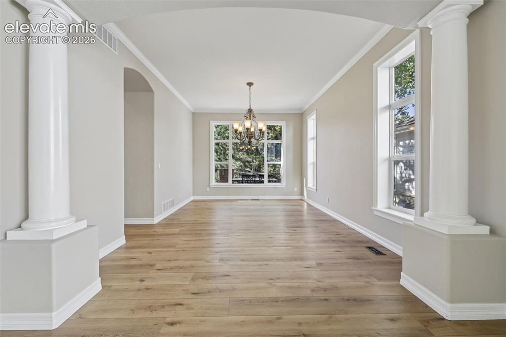 Image 9 of 49: Arched entryway with classic columns, wood-finish flooring, and a decorativ