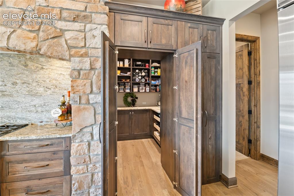 Image 13 of 50: Concealed entry to oversized walk-in pantry with custom cabinetry, blending