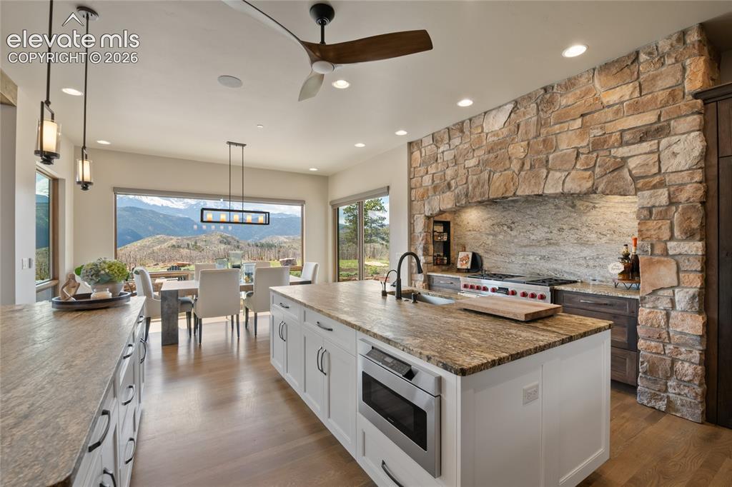 Image 15 of 50: Open-concept kitchen and dining with Wolf range, full-slab granite backspla